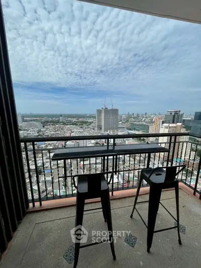 Stunning high-rise balcony view with cityscape and stylish seating, perfect for urban living.