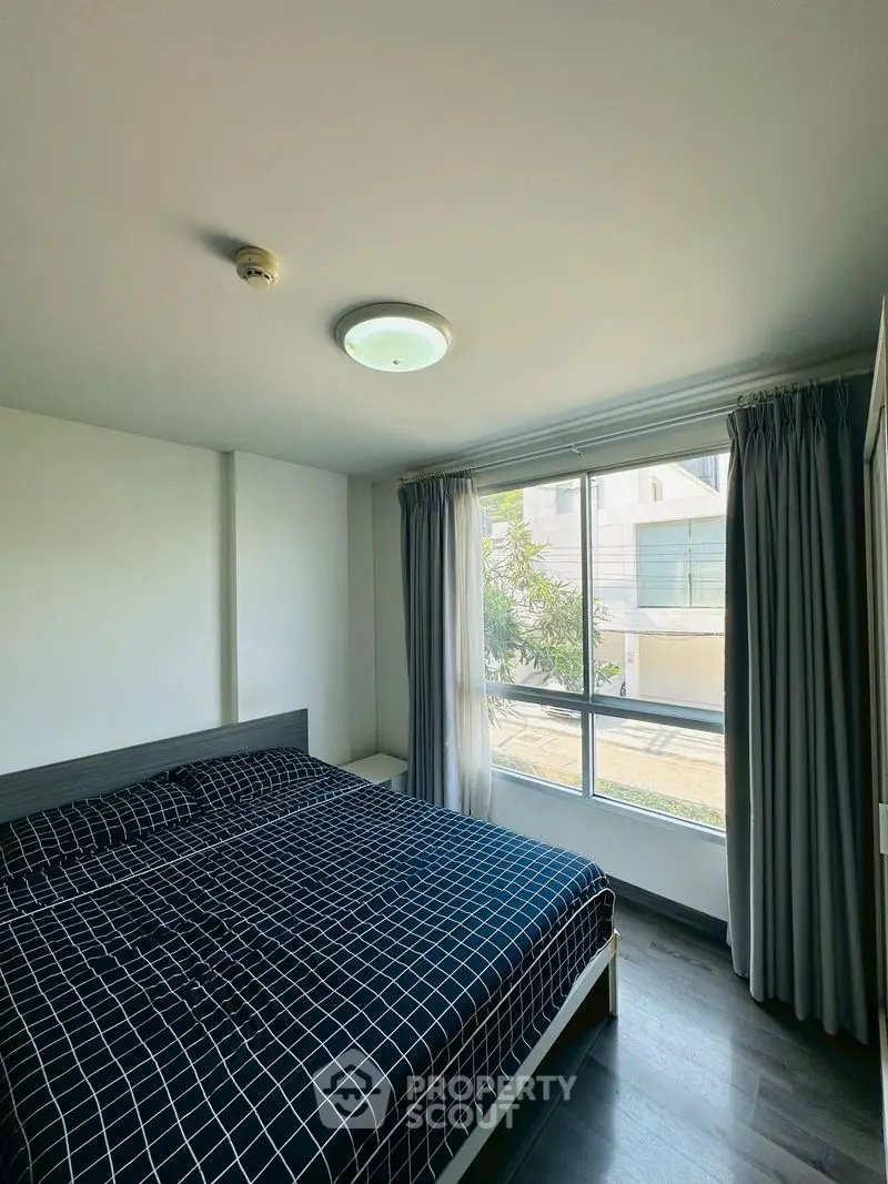 Cozy bedroom with large window and modern decor in a bright apartment.
