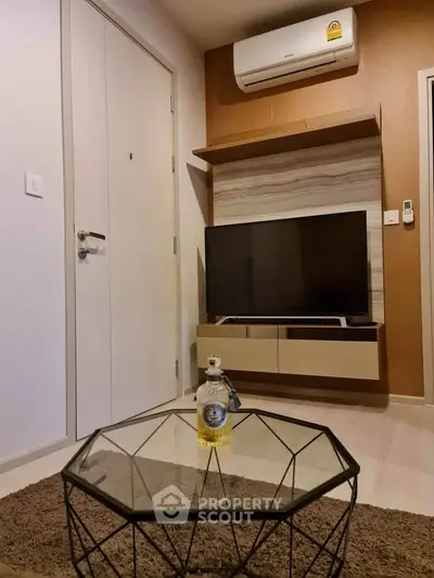 Modern living room with stylish TV setup and geometric glass coffee table.