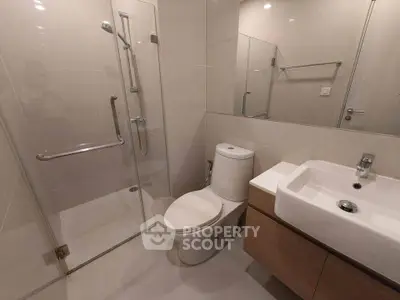 Modern bathroom with glass shower and sleek fixtures in contemporary apartment.