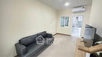 Modern living room with sleek black sofa and wall-mounted air conditioner