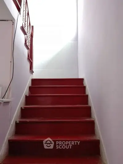 Red staircase leading to a bright upper floor in a residential property.