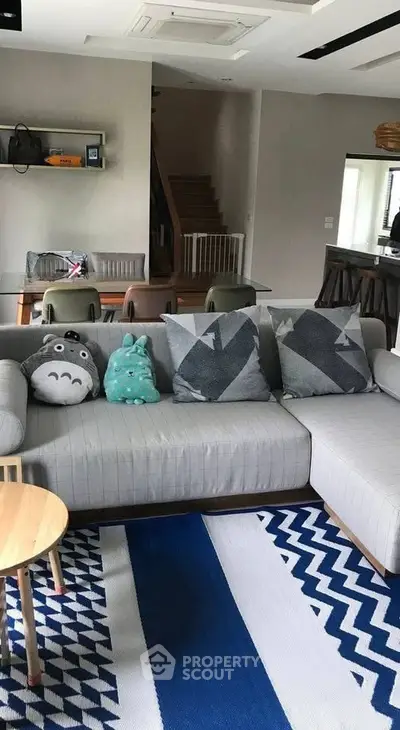 Stylish living room with modern gray sofa, geometric cushions, and playful decor accents.