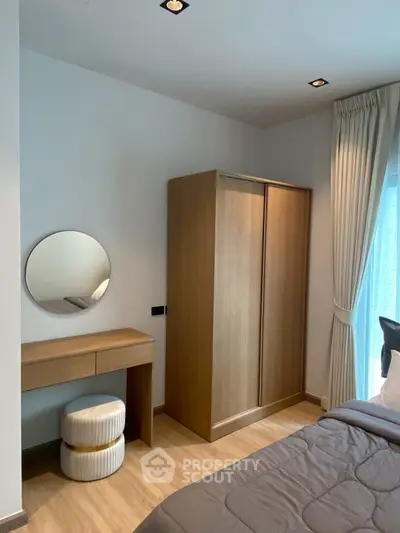 Modern bedroom with wooden wardrobe, round mirror, and elegant curtains.