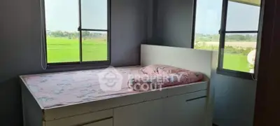 Cozy bedroom with scenic views of lush green fields through large windows.