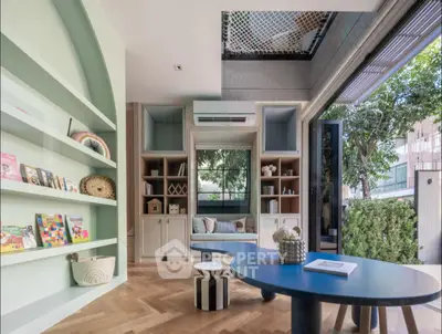 Modern living room with open layout and stylish decor, featuring large windows and built-in shelving.