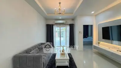 Elegant living room with modern decor, plush gray sofa, and stylish chandelier, perfect for relaxation.