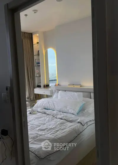 Cozy bedroom with modern decor and large window offering natural light.