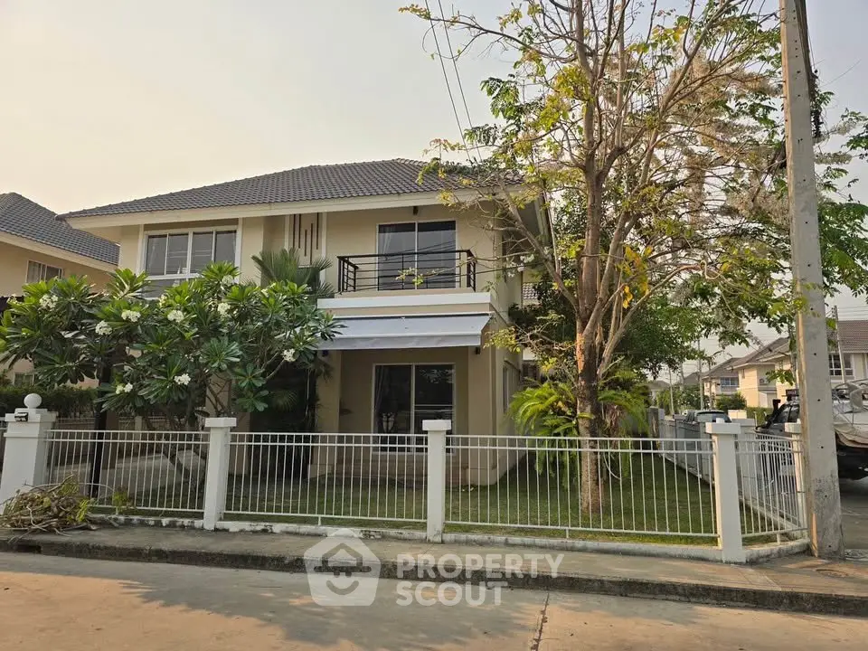 Charming two-story house with a fenced yard and lush greenery in a serene neighborhood.