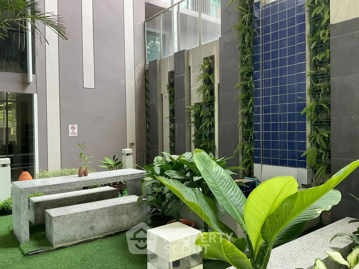 Modern building entrance with lush greenery and sleek design elements.