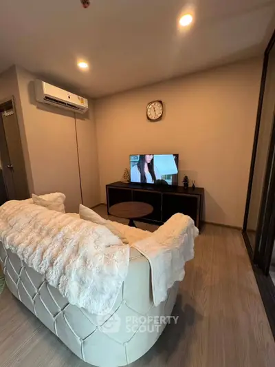 Cozy living room with plush sofa and wall-mounted TV, perfect for relaxation.