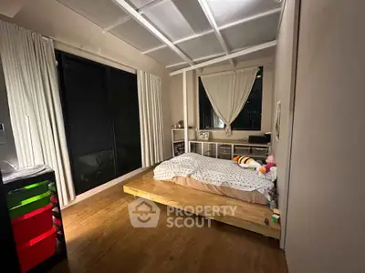 Modern bedroom with cozy wooden flooring and large windows for natural light.