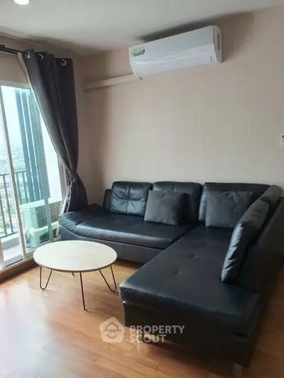 Modern living room with black leather sofa and city view balcony.
