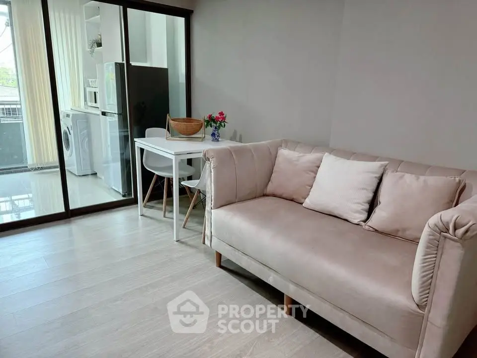 Modern living room with cozy sofa and dining area, featuring a washing machine and sleek kitchen appliances.