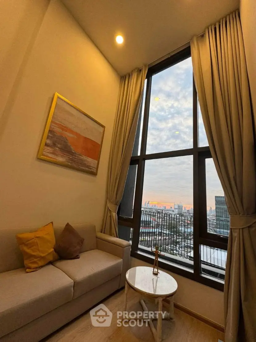 Stylish living room with large window offering stunning city view, cozy sofa, and elegant decor.