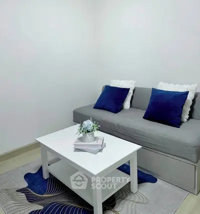 Cozy living room with modern gray sofa, blue cushions, and stylish white coffee table.