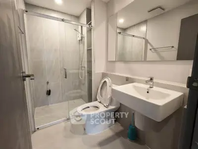 Modern bathroom with glass shower and sleek fixtures in contemporary apartment.