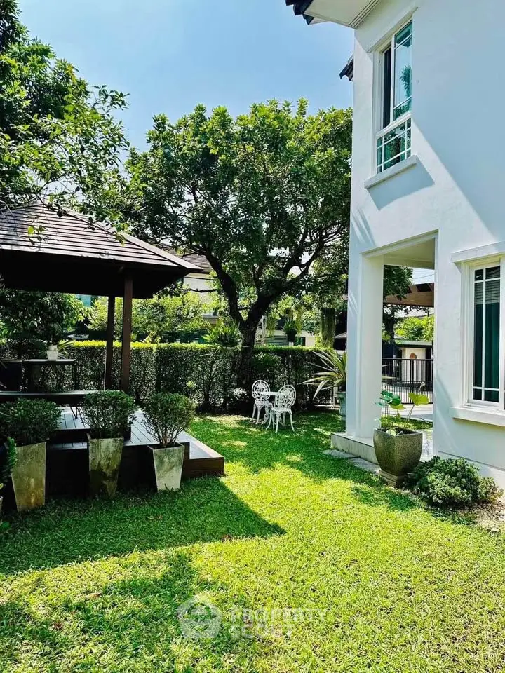 Charming garden view with lush greenery and elegant outdoor seating in a serene residential setting.
