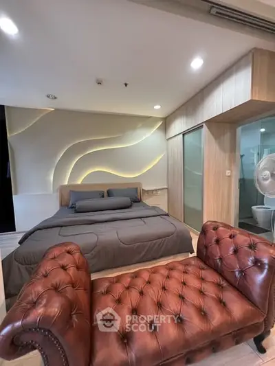 Luxurious modern bedroom with stylish lighting and elegant leather seating.