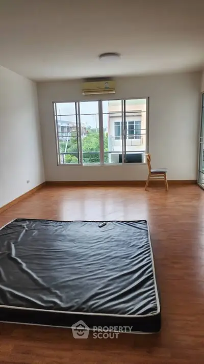 Spacious unfurnished bedroom with large windows and wooden flooring