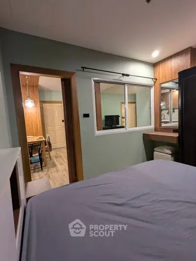 Modern bedroom with view into dining area, featuring stylish decor and cozy ambiance.