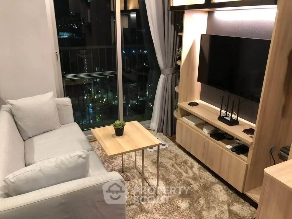 Modern living room with cozy sofa, stylish TV unit, and city view from balcony.
