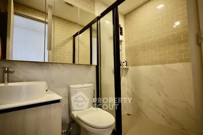 Modern bathroom with sleek design, featuring a glass shower enclosure and stylish fixtures.