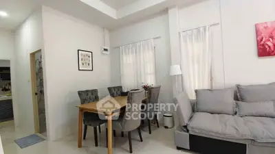 Cozy living room with dining area, featuring elegant gray chairs and a comfortable sofa.