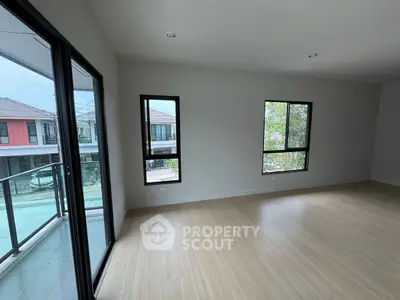 Spacious empty room with large windows and balcony access in modern home.