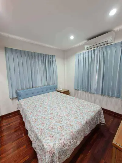 Cozy bedroom with wooden flooring and air conditioning