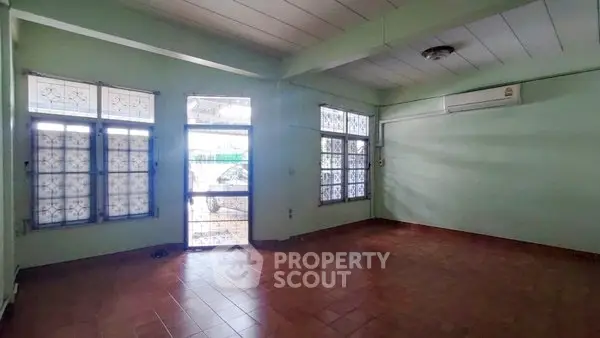 Spacious living room with tiled floor and large windows, perfect for natural light.