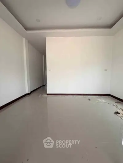 Spacious empty room with glossy tiled floor and white walls, perfect for customization.