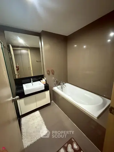 Modern bathroom with sleek design featuring bathtub and vanity in a cozy setting.
