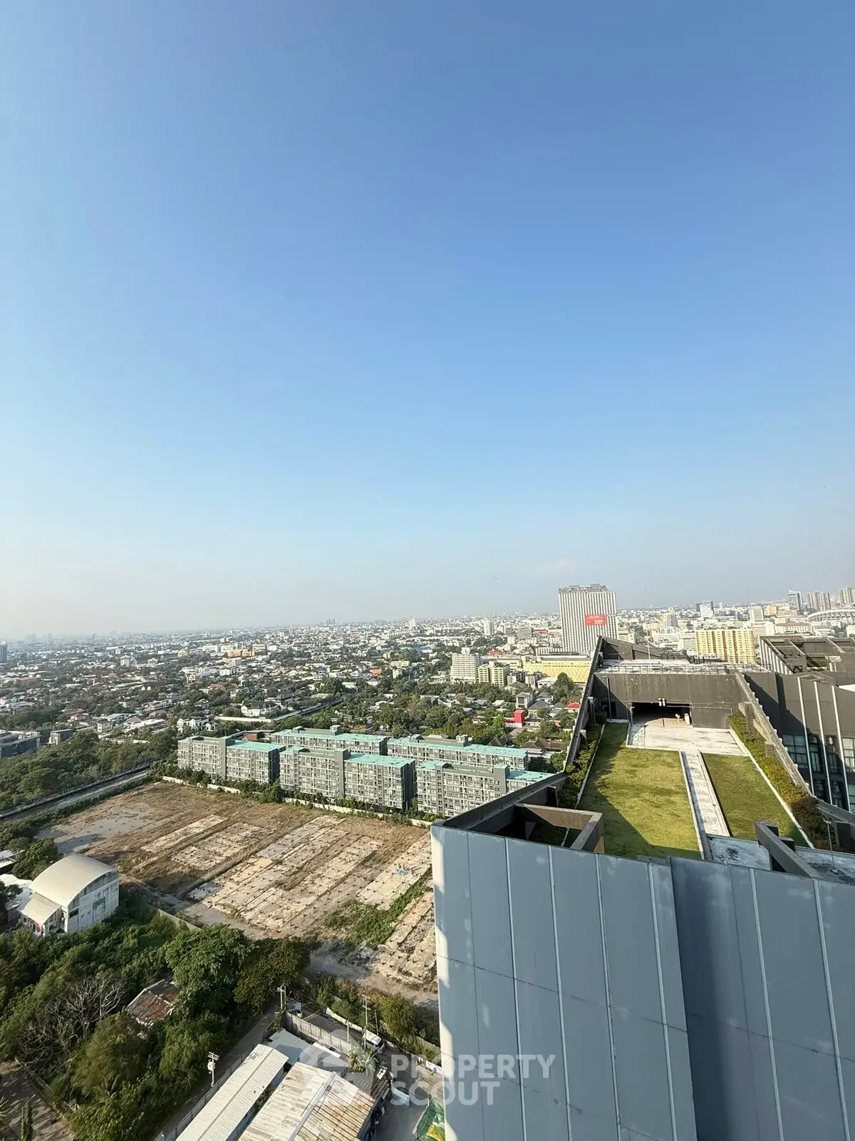 Stunning cityscape view from a modern rooftop with lush green terrace, perfect for urban living.