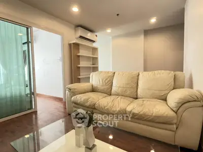 Modern living room with plush sofa and glass coffee table in a cozy apartment setting.