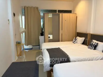 Spacious bedroom with three beds and modern decor, ideal for family living.