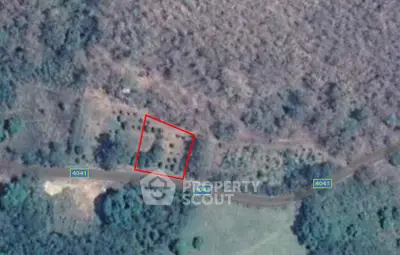 Aerial view of a plot of land with surrounding greenery and road access, ideal for development.