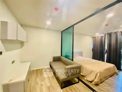 Modern studio apartment with sleek design and glass partition separating living and sleeping areas.