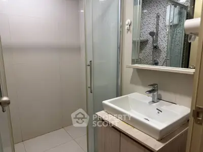 Modern bathroom with glass shower and sleek sink in contemporary apartment.