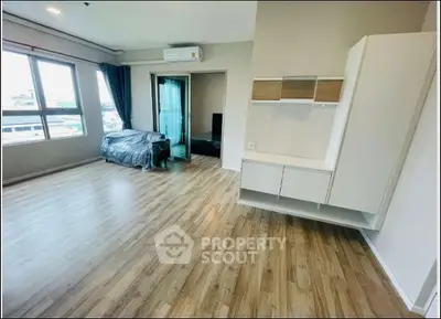 Spacious modern living room with wooden flooring and large windows for natural light.