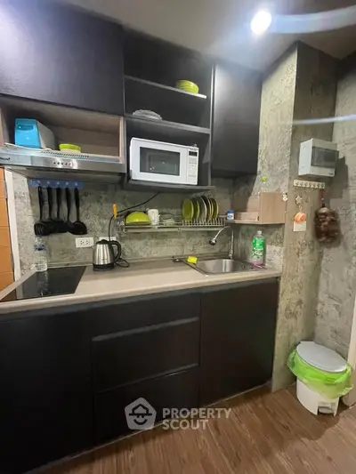 Modern compact kitchen with sleek black cabinets and stainless steel appliances.