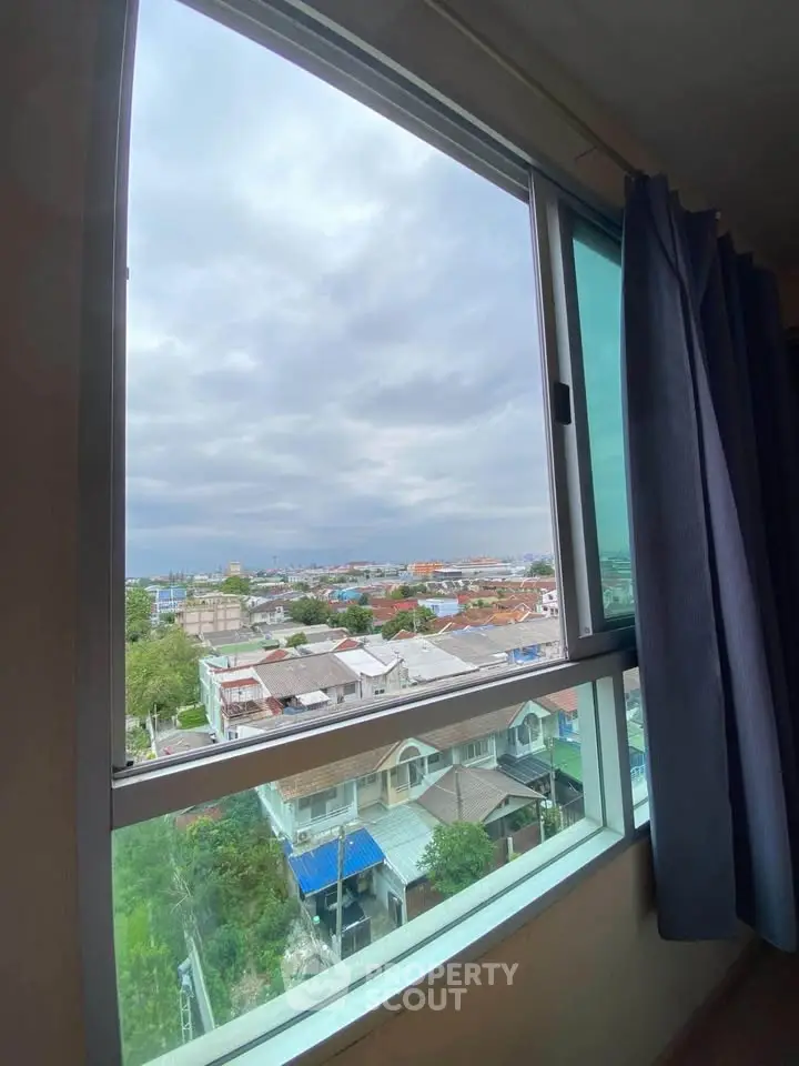 Stunning cityscape view from a high-rise apartment window with blue curtains.