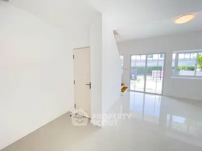 Bright and spacious modern living room with large windows and glossy floors.