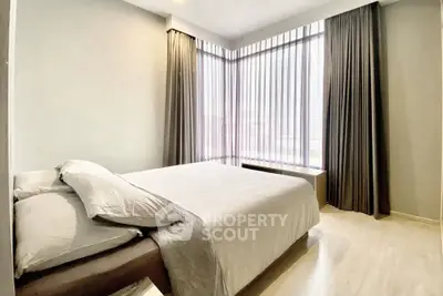 Spacious bedroom with large windows and elegant curtains in modern apartment