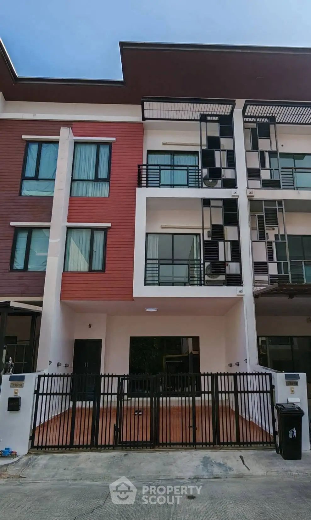 Modern townhouse exterior with gated entrance and stylish facade in urban setting.