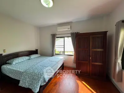 Spacious bedroom with wooden flooring and ample natural light
