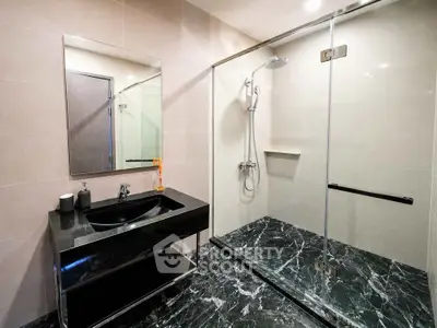 Modern bathroom with sleek black marble flooring and glass shower enclosure