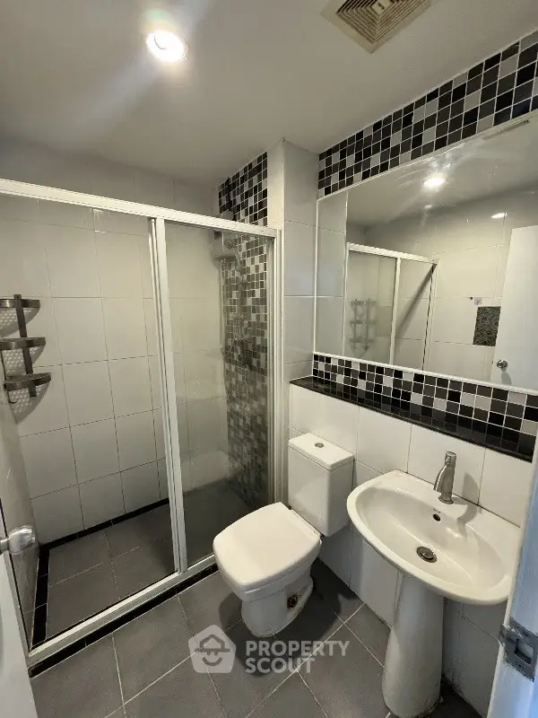 Modern bathroom with sleek shower enclosure and stylish black and white tile accents.
