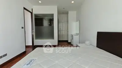 Spacious bedroom with modern design and ample natural light, featuring a large bed and sleek wooden flooring.
