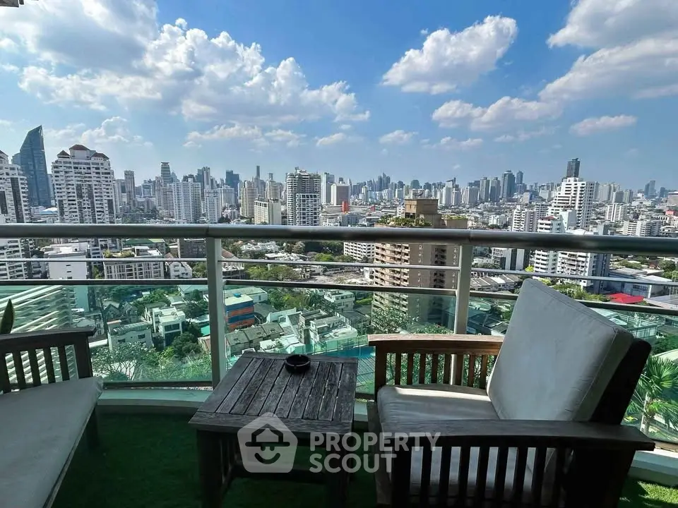Stunning cityscape view from a high-rise balcony with cozy seating area.